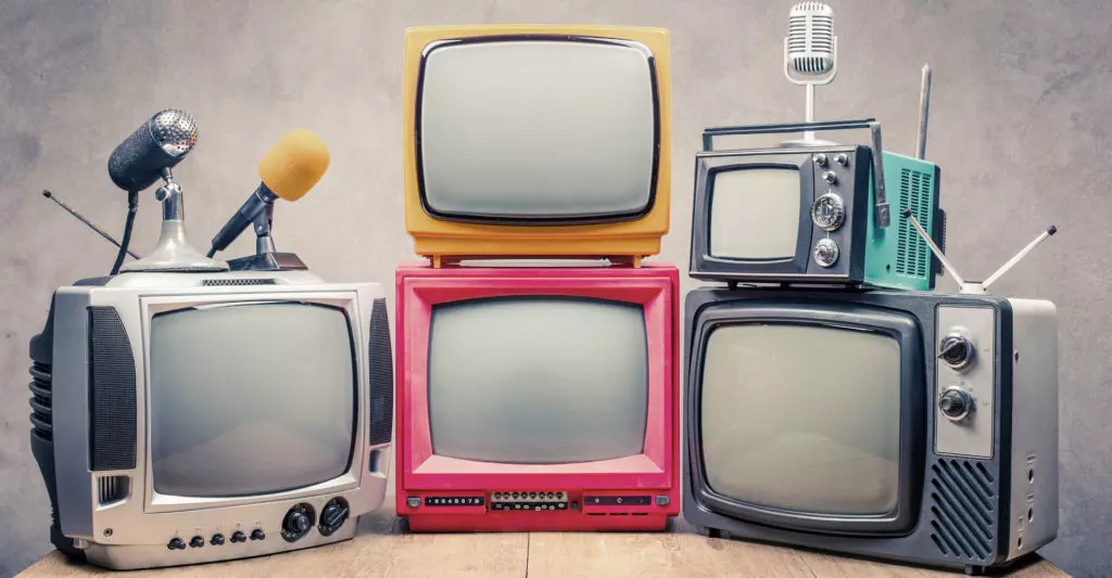 Fünf altmodische Fernseher sind nebeneinander aufgereiht und zeigen zum Betrachter.